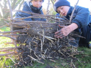 two boys building a wall with sticks and mud