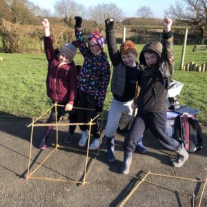 4 children cheering with a cube they made out of bamboo canes during a castles workshop