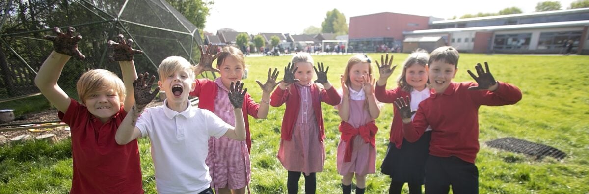 A group of children with muddy hands smiling and laughing