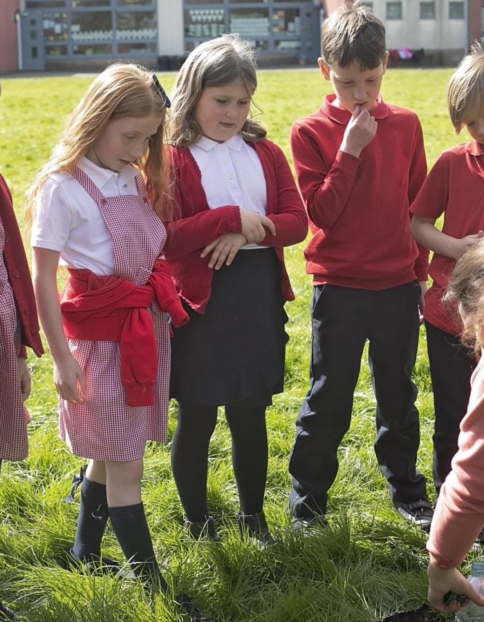 A group of children focusing on an adult demonstrating an outdoor activity