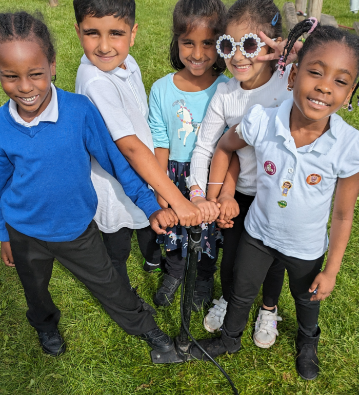 5 smiling children with their hand on a stirrup pump, ready to launch a rocket
