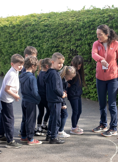 A primary teacher delivering an outdoor lesson to a class