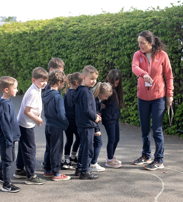 A primary teacher delivering an outdoor lesson to a class
