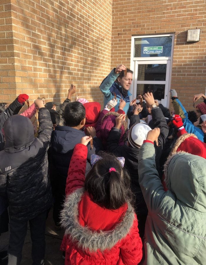 a teacher showing a class of children a leaf