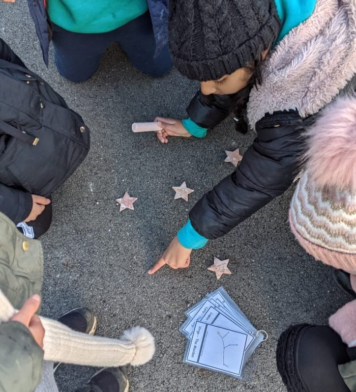 A child creating star constellations on the playground with chalk