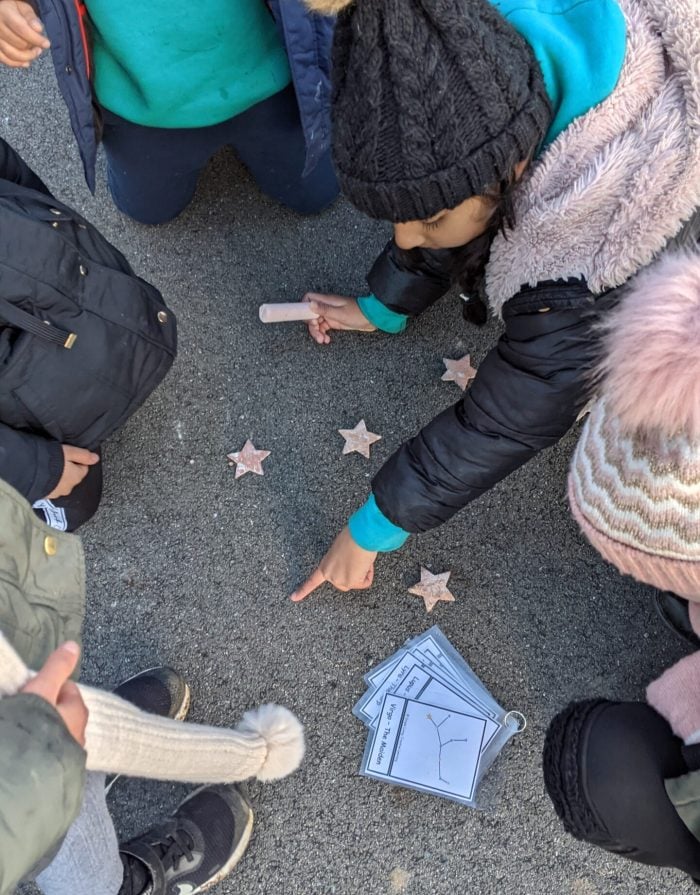 A child creating star constellations on the playground with chalk
