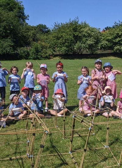 A class of children holding up their flags in front of the castle they built together