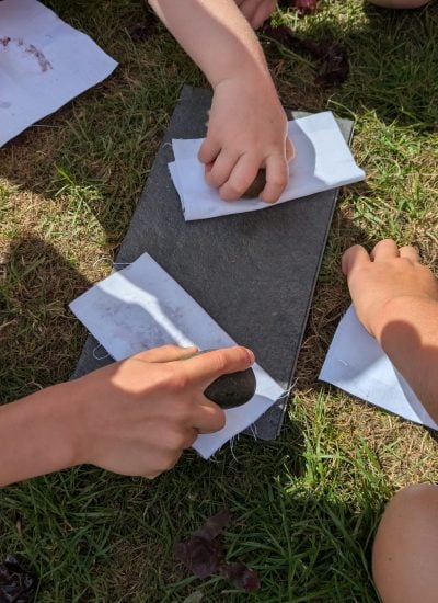 Children creating seaweed prints by hitting cotton with stones