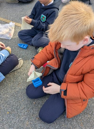 A boy attaching a sail to a small model boat