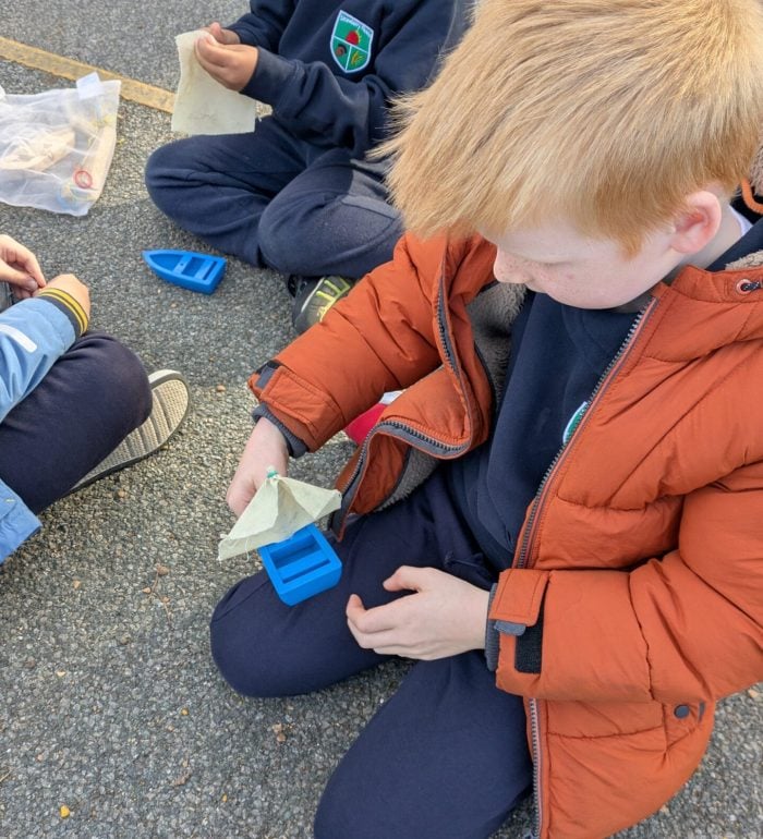 A boy attaching a sail to a small model boat