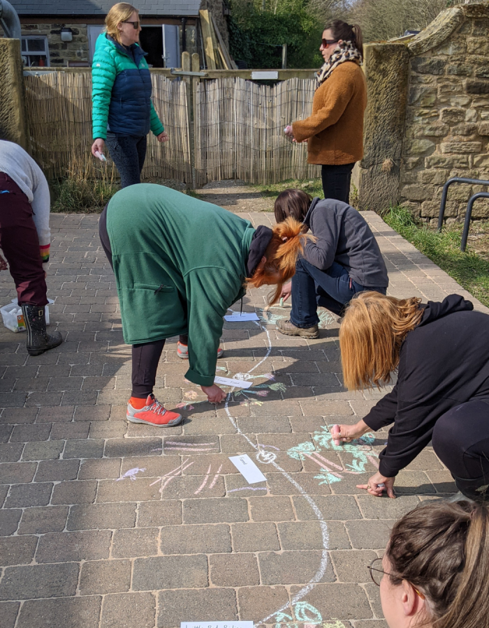 Teachers drawing a story map on the ground with chalk